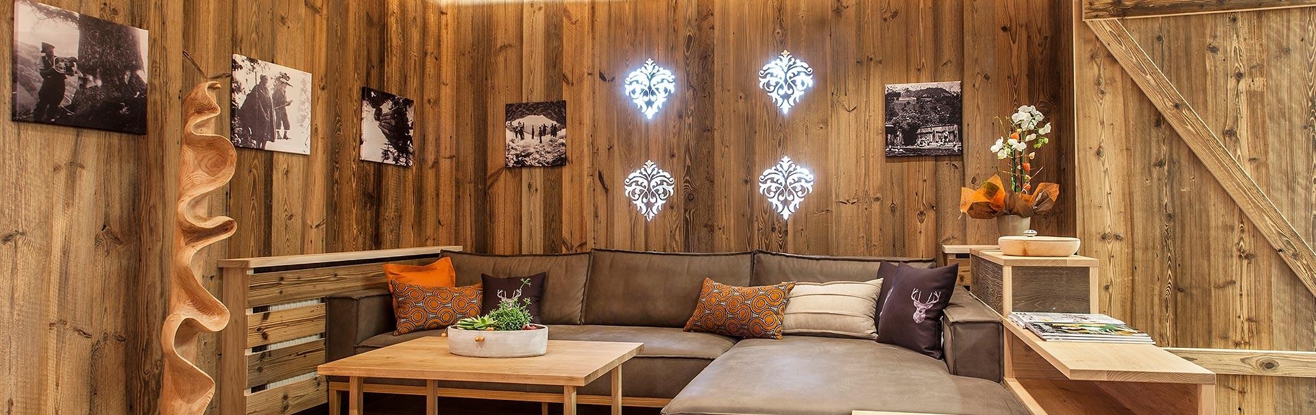 Altholz Wohnzimmer Schwarz-Weiß Bilder beleuchtete Ornamente und Ledersofa